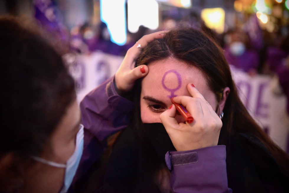 Una mujer se pinta un símbolo de la mujer en una marcha del 8M @Javier Alborés