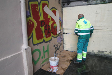 Un operario de la concesionaria de limpieza pinta sobre un grafiti en las escaleras de o  quintana