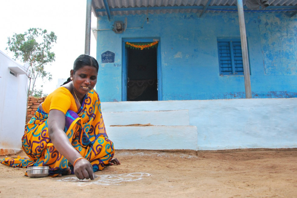 Una mujer india ante su vivienda