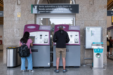 Dos personas compran billetes en los cajeros de venta automática en la estación de trenes, a 24  de agosto de 2022, en Santiago de Compostela, ep