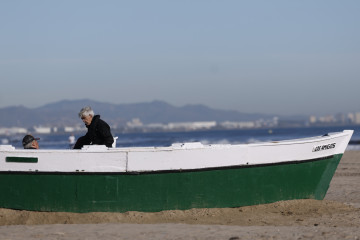 VALENCIA, 24/12/2024.- Dos personas disfrutan de una jornada soleada en la playa de la Malvarrosa, este martes, día de nochebuena. EFE/Kai Forsterling