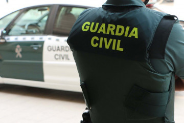 Archivo - Un agente de la Guardia Civil, de espaldas, junto a un vehículo oficial. Imagen de archivo