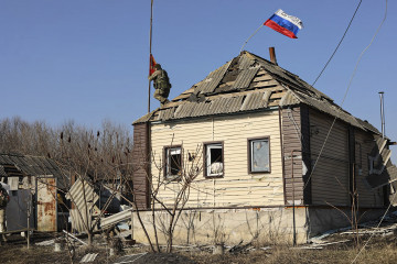 Undisclosed (Russian Federation), 14/03/2025.- A handout photo made available by the Russian Defence Ministry's press-service shows a Russian serviceman installing a red flag on the roof of a damaged 